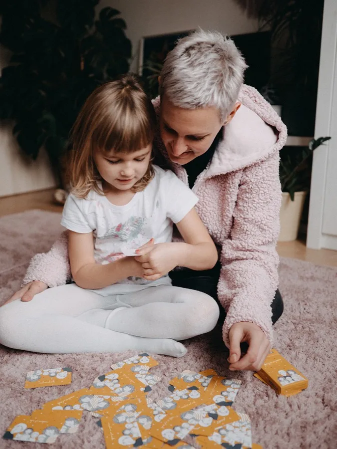 Mama z córką oglądają karty na dywanie
